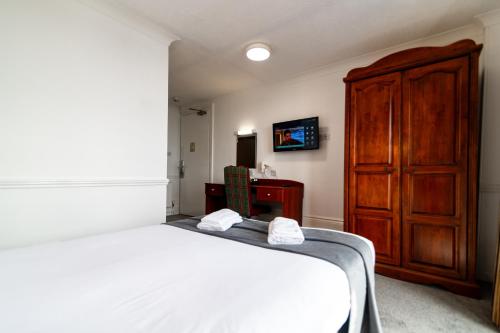 a bedroom with a bed and a wooden cabinet at The Southcliff Hotel in Folkestone