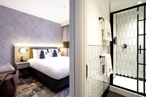 a hotel room with a bed and a walk in shower at The Met Hotel Leeds - Newly Refurbished in Leeds