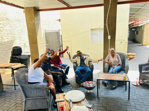 a group of people sitting in chairs on a patio at Palmetto guesthouse in Mahikeng