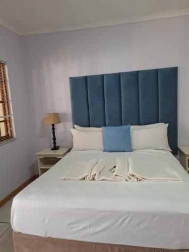 a large bed with a blue headboard and white pillows at Palmetto guesthouse in Mahikeng