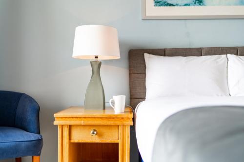 a bedside table with a lamp and a blue chair at The Southcliff Hotel in Folkestone