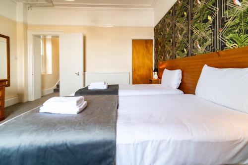 a bedroom with two beds with white sheets at The Southcliff Hotel in Folkestone