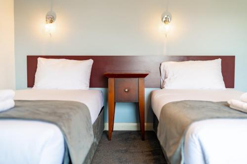 two beds in a room with a table between them at The Southcliff Hotel in Folkestone