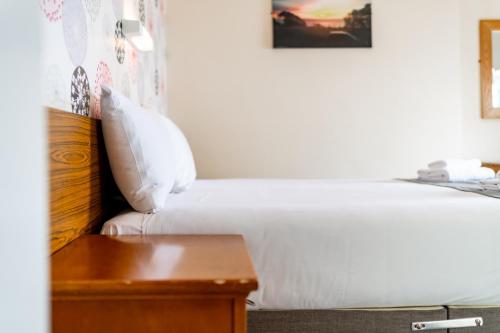 a bedroom with a white bed and a wooden table at The Southcliff Hotel in Folkestone