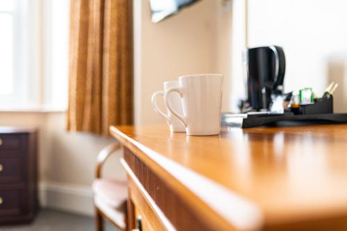 a coffee cup sitting on top of a wooden desk at The Southcliff Hotel in Folkestone