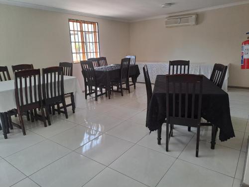 a dining room with black tables and chairs at Palmetto guesthouse in Mahikeng