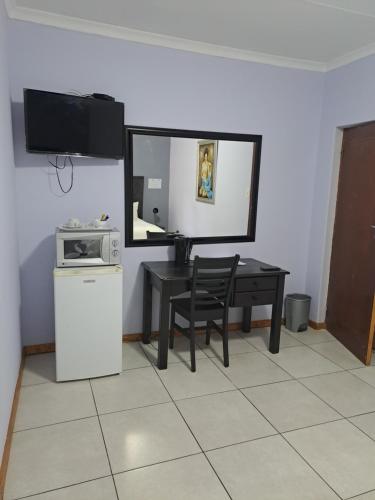 a kitchen with a table and a microwave and a table with a chair at Palmetto guesthouse in Mahikeng