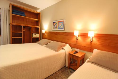 two beds in a hotel room with two lamps at Pousada Villa Capivary Campos do Jordão in Campos do Jordão