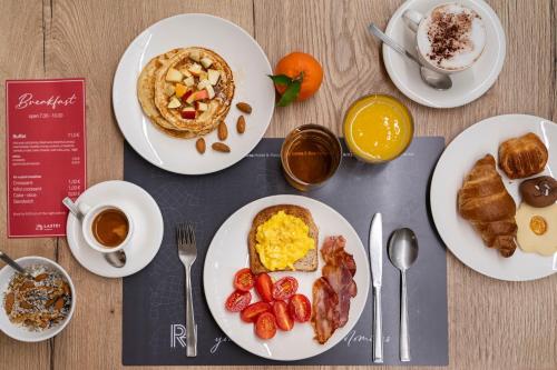 a table with plates of breakfast foods and a book at Residence Lastei in San Martino di Castrozza