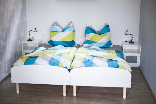 1 dormitorio con cama blanca y almohadas coloridas en Hoofer Apartments, en Schauenburg