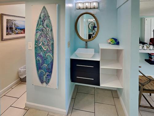 a bathroom with a sink and a surfboard on the wall at The Salty Fountain in Seabreeze