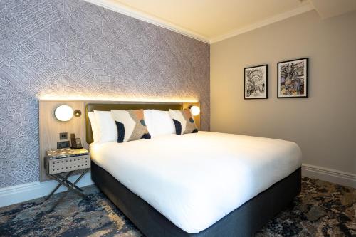a bedroom with a large white bed and a wall at The Met Hotel Leeds - Newly Refurbished in Leeds