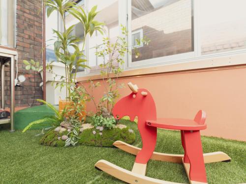 a red rocking horse in the yard of a house at Chun cheon Bongstay 2nd Floor in Chuncheon