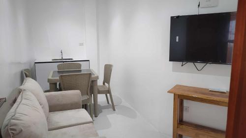 a living room with a table and a television on a wall at Ola De Baler Hotel in Baler