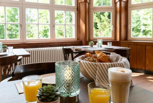 a table with a basket of bread and glasses of orange juice at Wohnpark Hotel Heppenheim in Heppenheim an der Bergstrasse