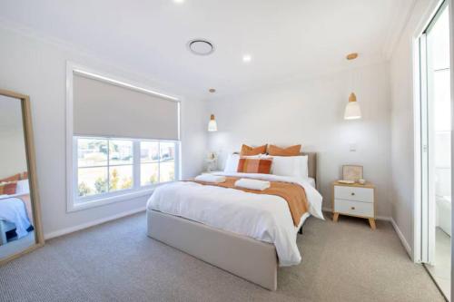 a white bedroom with a large bed and a window at Macintyre House in Dubbo