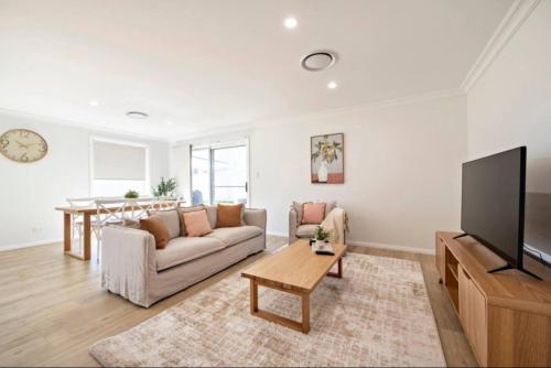 a living room with a couch and a tv at Macintyre House in Dubbo