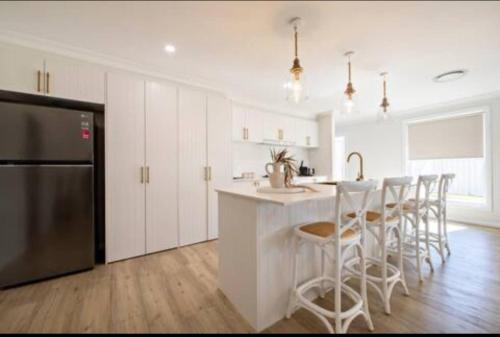 a kitchen with white cabinets and a kitchen island with bar stools at Macintyre House in Dubbo