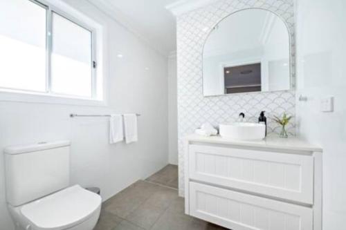 a white bathroom with a toilet and a sink at Macintyre House in Dubbo