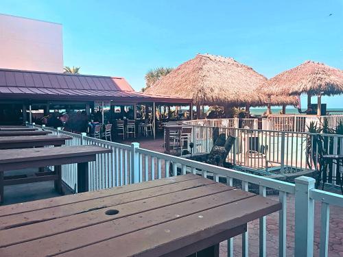 a restaurant with tables and straw umbrellas on the beach at The Salty Fountain in Seabreeze