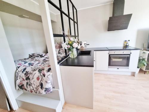 Una pequeña cocina blanca con una cama en una habitación en Modern apartment in the heart of Drammen, en Drammen