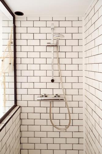 a bathroom with a shower with white brick walls at Vacances à l'école ! in Cléden-Cap-Sizun