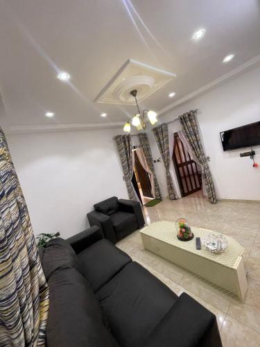 a living room with a black couch and a table at DTS-TOGO Properties in Komé