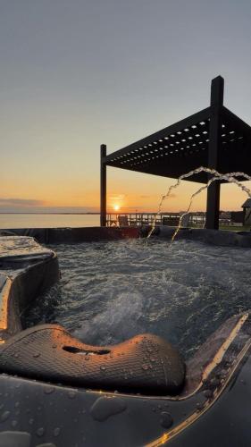 a hot tub with an umbrella and the ocean at Private beach on a fenced in property sunset views in Hampton Bays