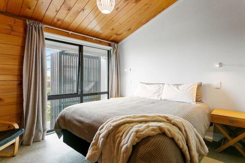 a bedroom with a bed and a large window at Modern Townhouse, Stunning Views in Taupo