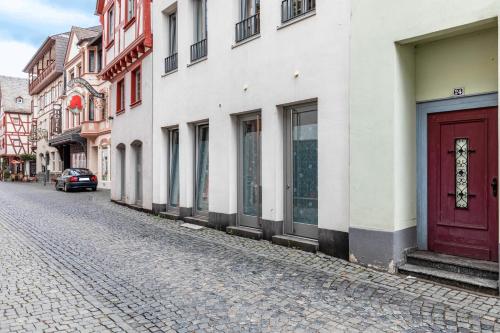 a cobblestone street with buildings and a red door at Bacchus Holiday Homes in Bacharach