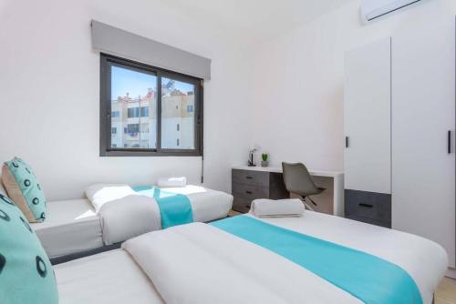 a bedroom with two beds and a desk and a window at Polka 2BR Apartment & Balcony in Batroun 