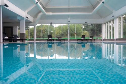 a large swimming pool with chairs in a building at Macdonald Craxton Wood Hotel & Spa in Ledsham