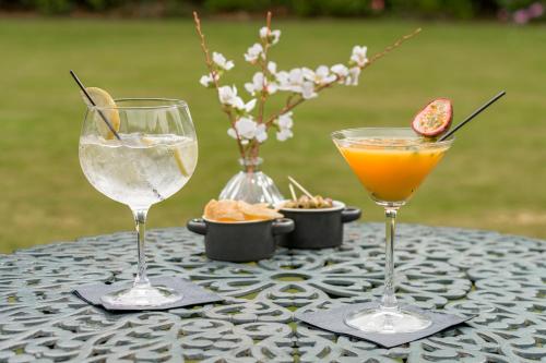two wine glasses sitting on a table with a drink at Macdonald Craxton Wood Hotel & Spa in Ledsham