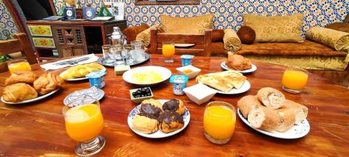 een tafel met borden vol eten en sinaasappelsap bij Dar Ahl Tadla in Fès