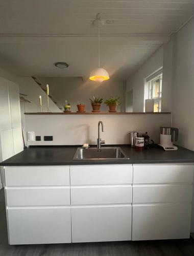 a kitchen with white cabinets and a sink at Solskinshuset in Hasle