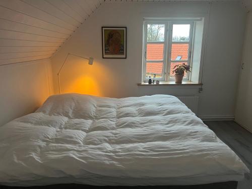 un grande letto bianco in una stanza con una finestra di Solskinshuset a Hasle