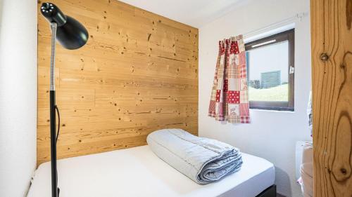 une chambre avec un lit avec une lampe et un mur en bois dans l'établissement Grande Neige N 10 - 2P4, à Morillon