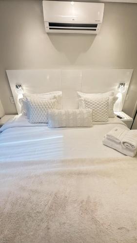 a large bed with white sheets and pillows at Moema Times Square SP - Luxury Suíte in Sao Paulo