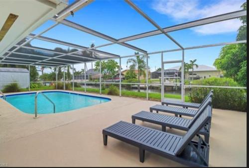 a patio with two benches and a swimming pool at Renovated Modern Home with Big Pool & Ocean Access in North Fort Myers
