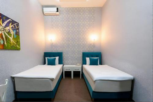 two beds in a room with blue chairs at Nizami Hotel Baku in Baku