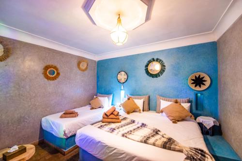 two beds in a room with blue walls and mirrors at KOUTOBIA ROYAL in Marrakech