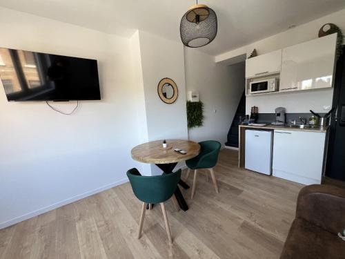 a living room with a table and chairs and a kitchen at Le Jardin Botanique in Lens
