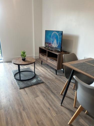 a living room with a tv and a table at Cozy, Stylish Modern 2 Bedroom Entire Flat in Manchester