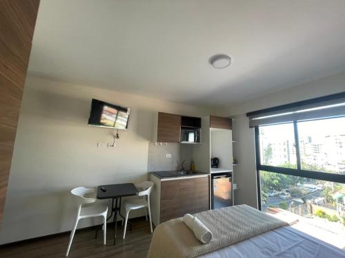 a bedroom with a bed and a table and a kitchen at Smart suite in Cochabamba