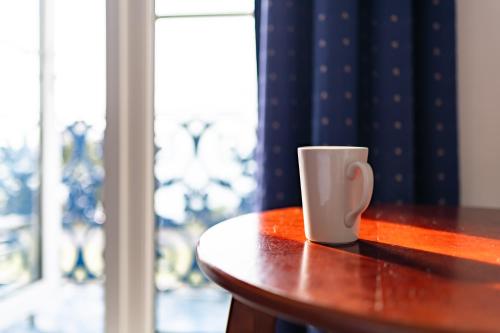 a cup sitting on a table next to a window at The Southcliff Hotel in Folkestone