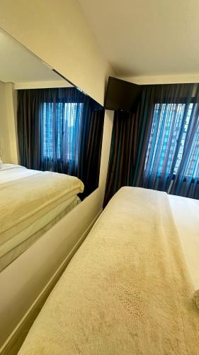 a bedroom with two beds and two windows at Moema Times Square SP - Luxury Suíte in Sao Paulo