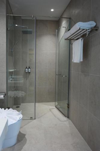 a bathroom with a glass shower and a toilet at Hotel Whitt Hua Hin in Hua Hin