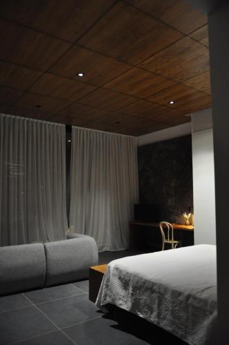 a bedroom with a bed and a couch and a desk at Boutique Hotel Bodega CICLO ANDINO in Perdriel