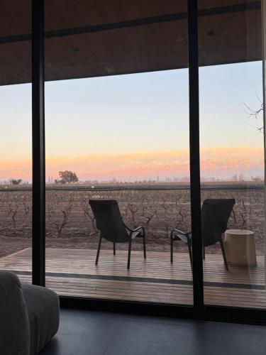 two chairs on a wooden deck with a view of a field at Boutique Hotel Bodega CICLO ANDINO in Perdriel