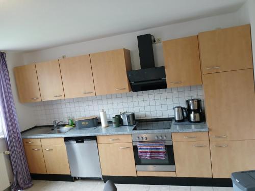 a kitchen with wooden cabinets and a stove top oven at Ferien- und Pferdehof Egelkraut "Feriendomizil am Meer" in Wangerland